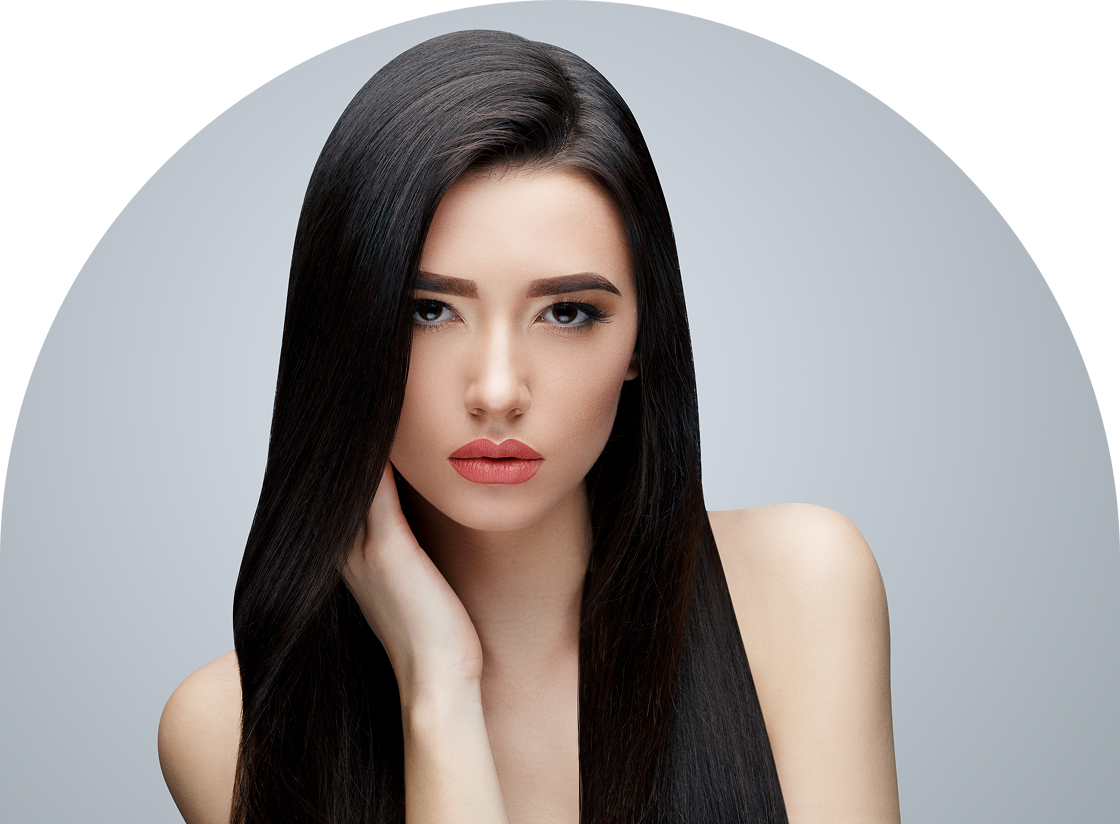 A person with long, straight black hair poses against a light gray background, gazing directly at the camera with a neutral expression, subtly hinting at their smooth skin achieved through expert waxing and hair removal techniques. One hand gracefully touches their neck.