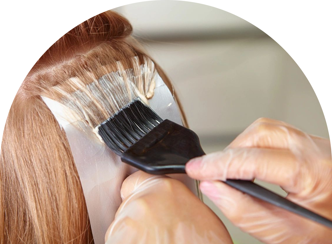 A person carefully applying hair dye with a brush on a sectioned piece of hair placed over foil, akin to the precision seen in professional waxing and hair removal services.