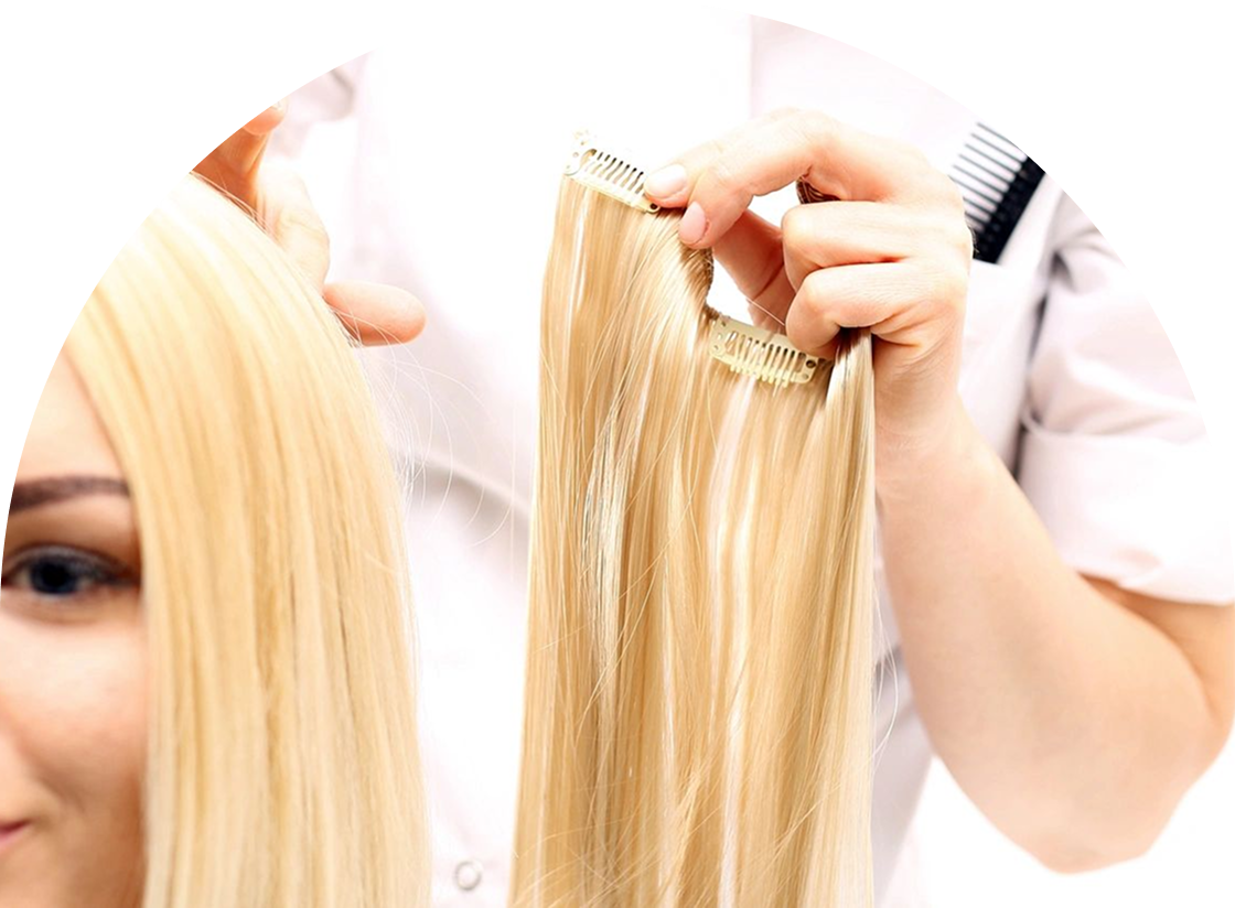 A person is holding a blonde hair extension near someone with similar hair, contemplating the perfect match after a session of waxing and hair removal.